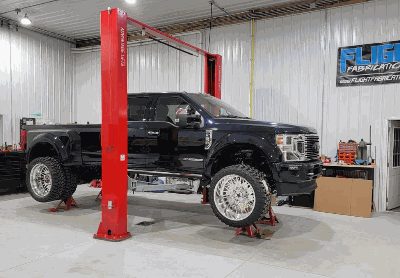 Advantage AL-12C 2-post lift with truck elevated in garage.
