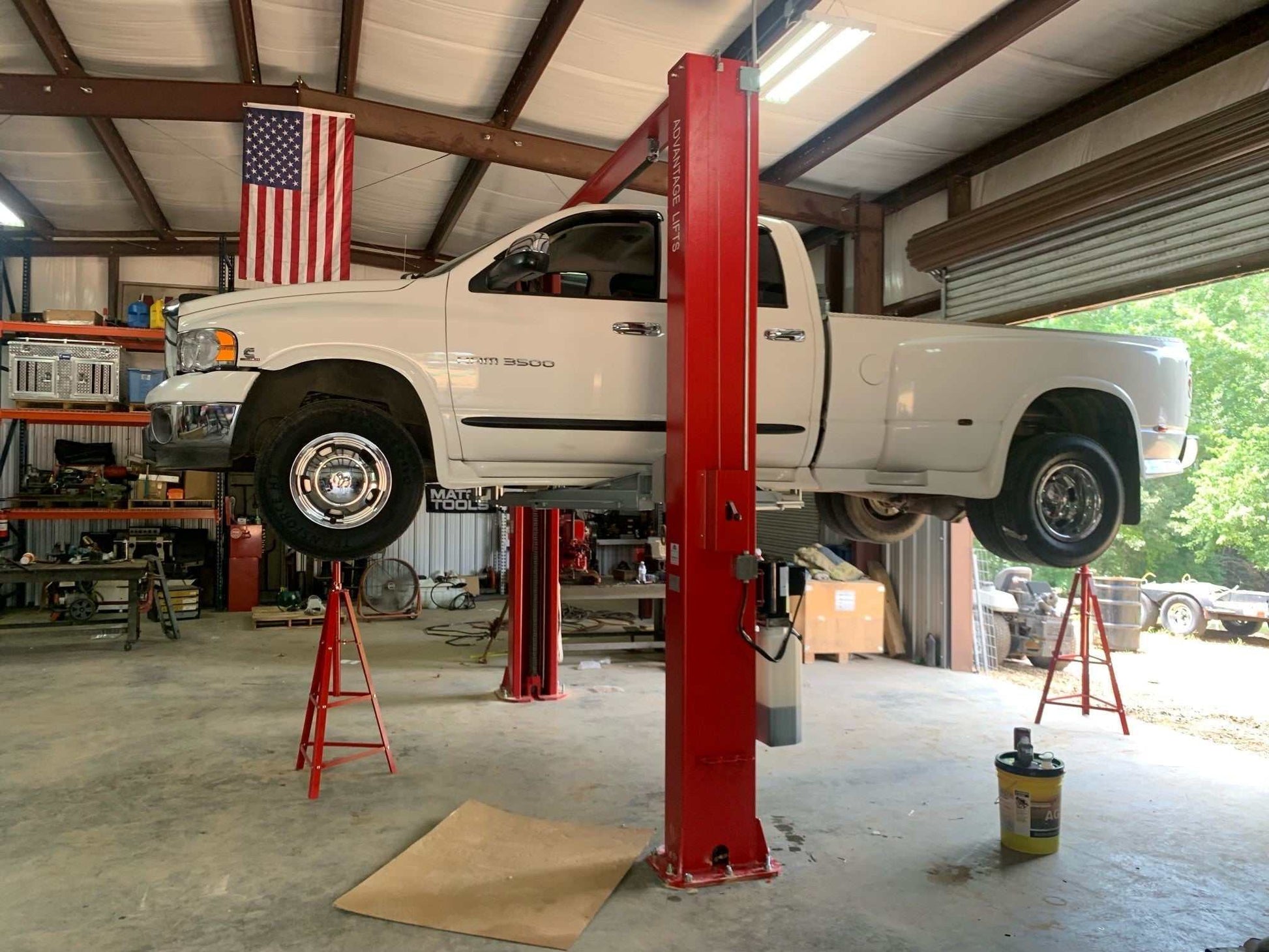 Advantage AL-12C 2-post lift raising white pickup truck in garage with red posts