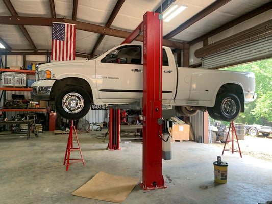 Advantage AL-12C 2-post lift raising white pickup truck in garage with red posts