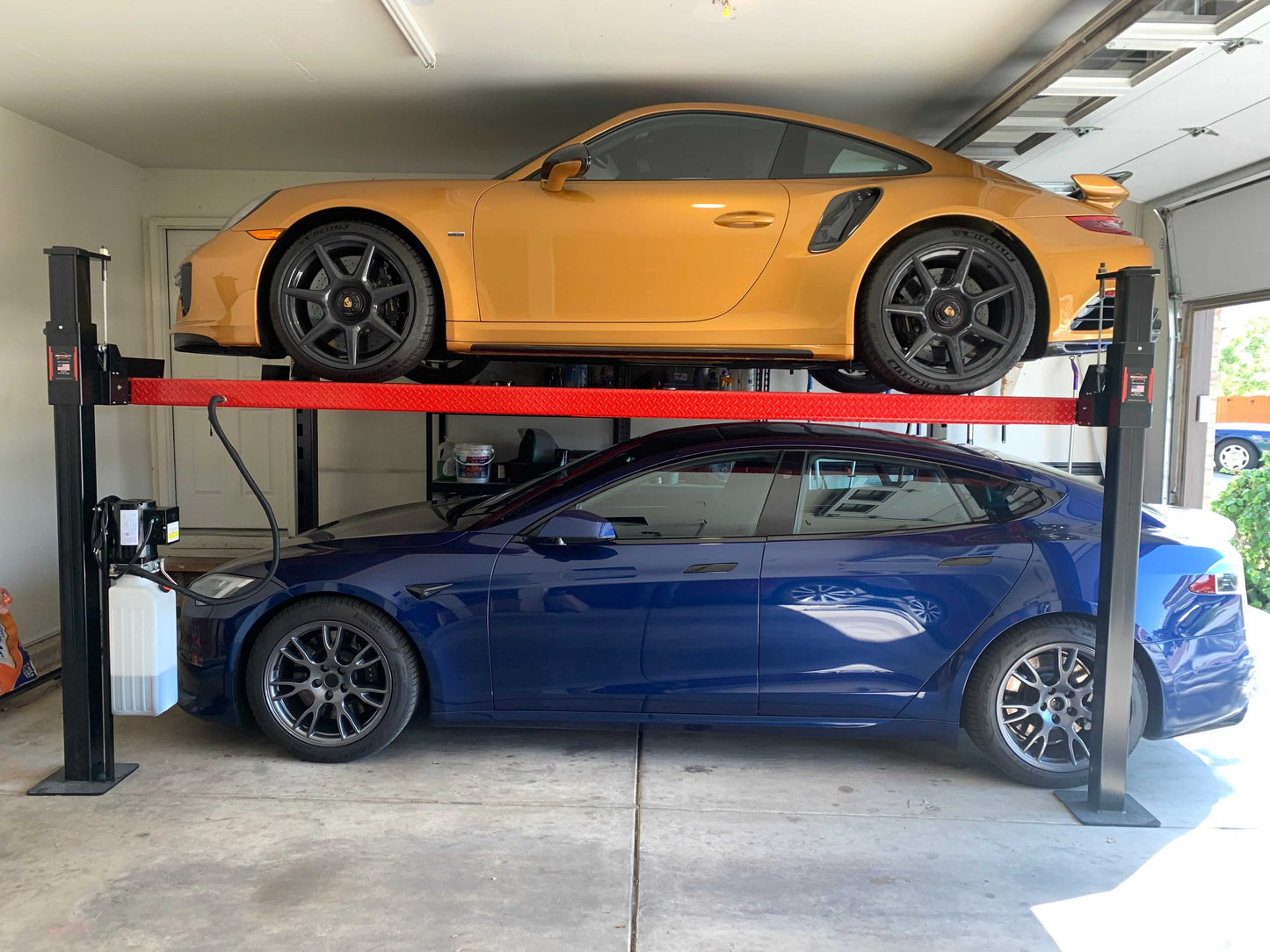 7,000 lbs Backyard Buddy Classic 4-post lift with two red cars in garage.