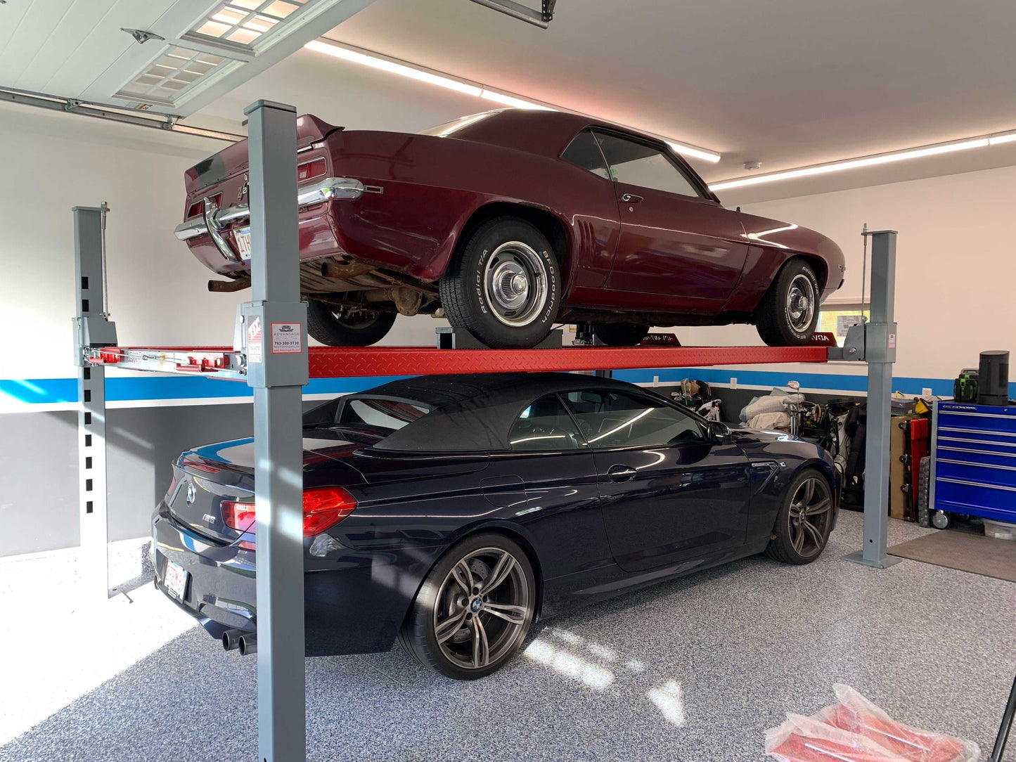 Advantage DX-9000-HD A maroon sports car on a car lift with a dark BMW car underneath, inside a home garage