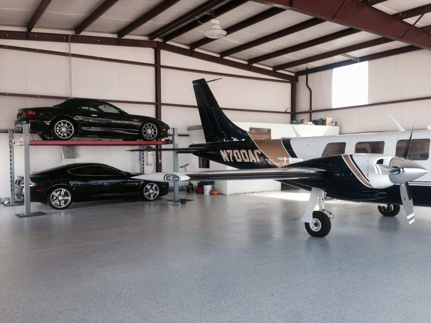 Advantage DX-9000-HD One car on top of a car lift and one car below the lift. An airplane is in the front. Photo is taken in an airplane hanger.