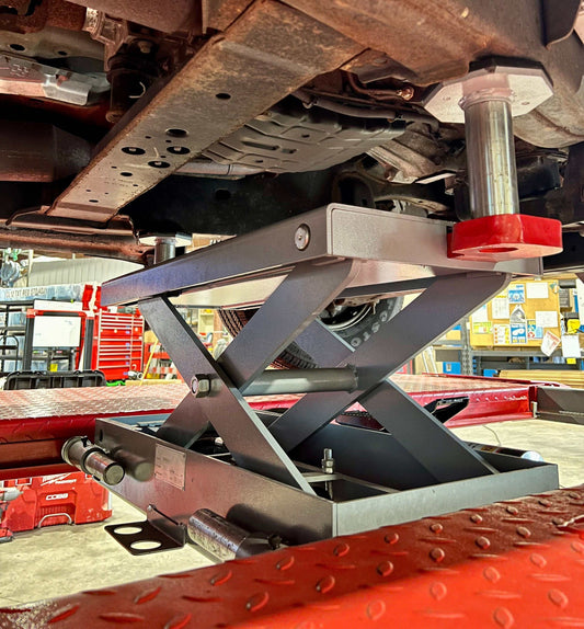 Advantage Lifts Rolling Air Jack lifting a vehicle on a 4-post lift in a workshop