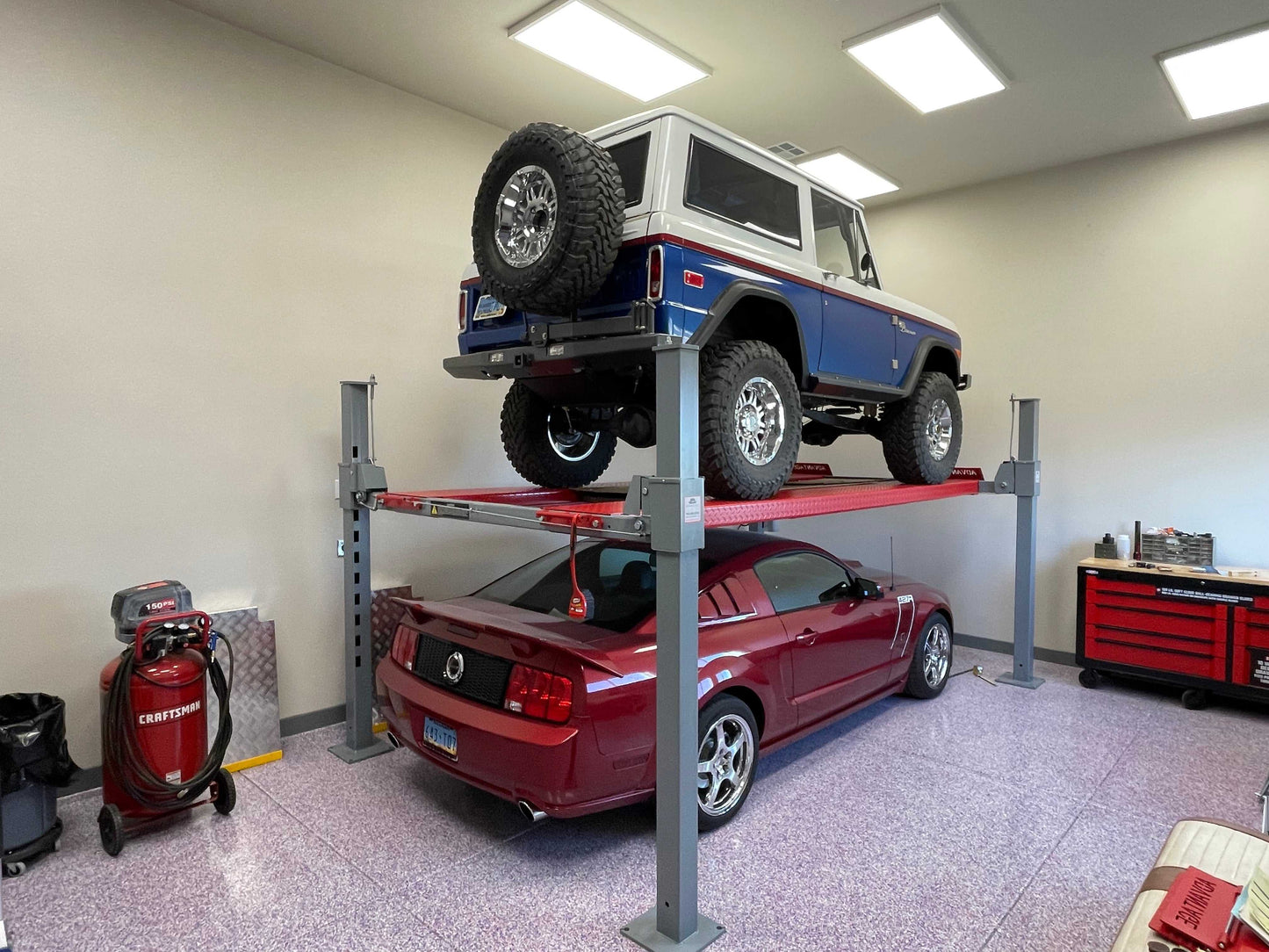 Advantage DX-9000-HD An old bronco on top of a car lift with a red sports car under it - taken inside a garage.