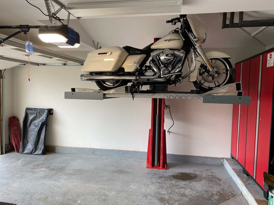 Single post motorcycle lift ML-2000 lifting a motorcycle in a garage for maintenance and storage.