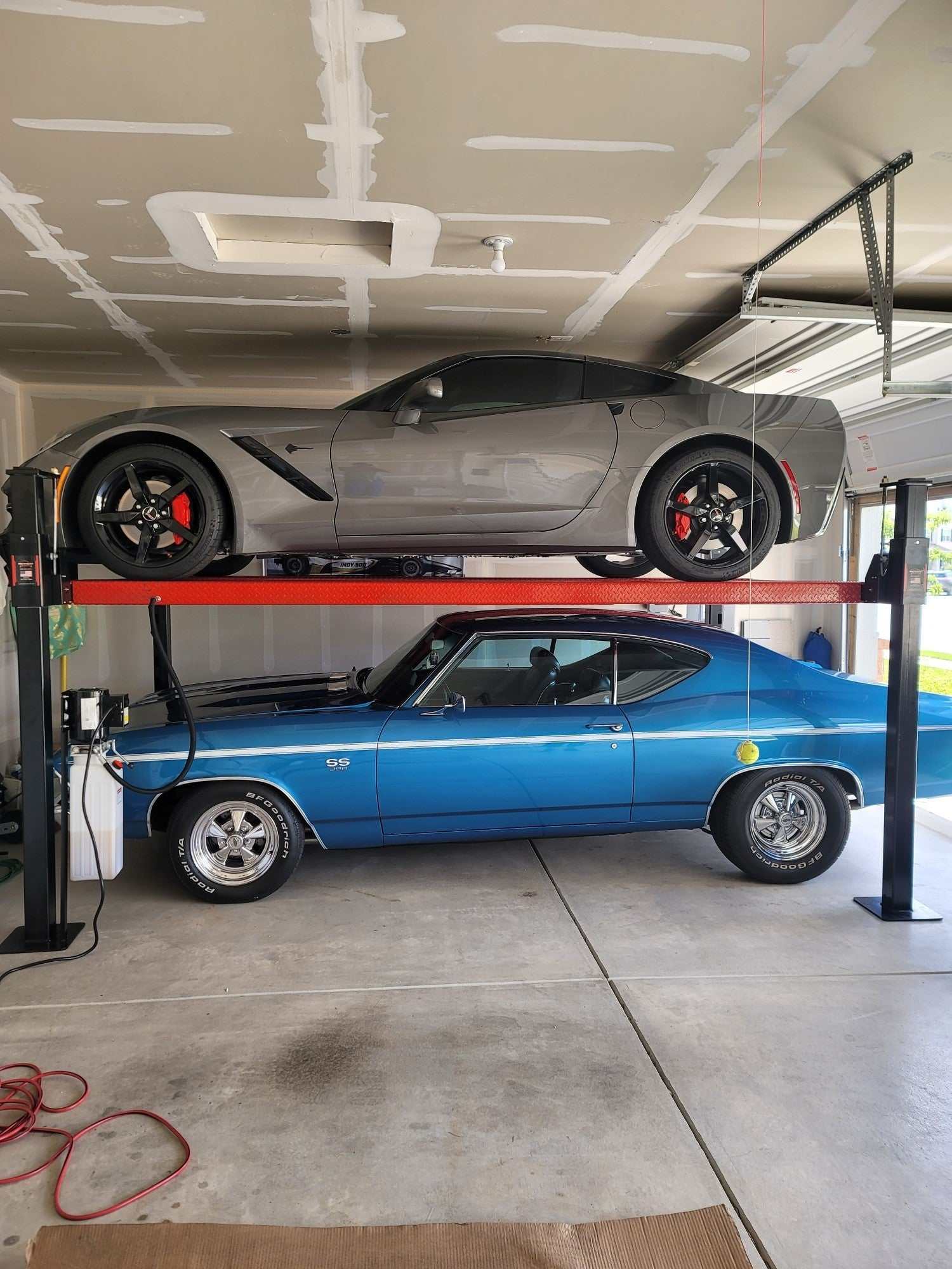 7,000 lbs Backyard Buddy Classic 4-post lift with two red cars in garage.