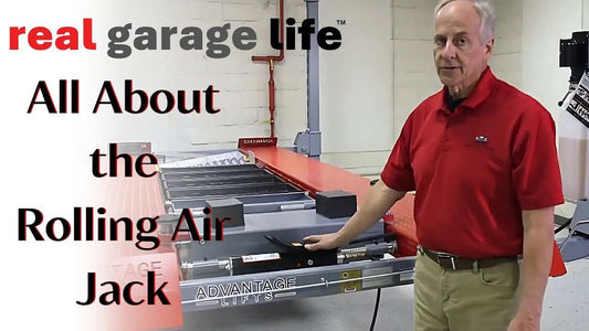 Man demonstrating the Advantage LIFT 9000 series rolling air jack on a vehicle lift platform in a garage setting.
